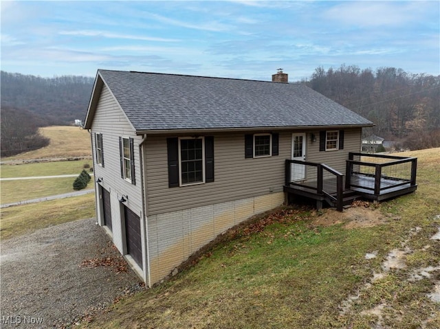 exterior space with a garage, a shingled roof, a chimney, and a front yard