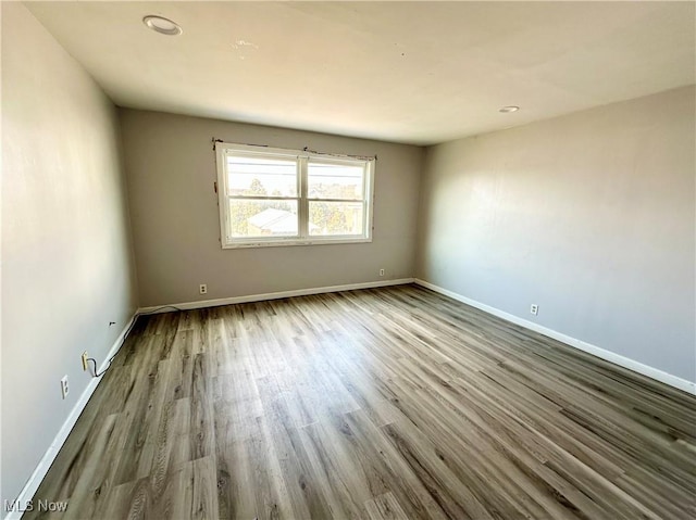 spare room with baseboards and wood finished floors