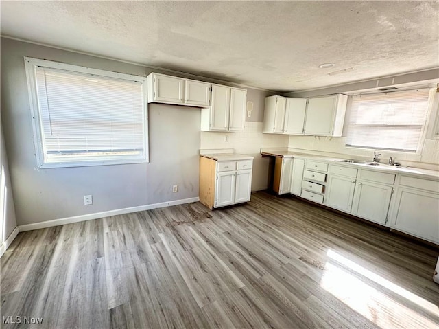 546 Rose St, Follansbee, WV 26037 - kitchen featuring baseboards, white cabinets, wood finished floors, a textured ceiling, and a sink