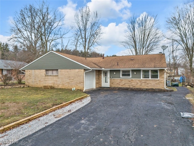 ranch-style house featuring a garage, brick siding, a shingled roof, driveway, and a front lawn