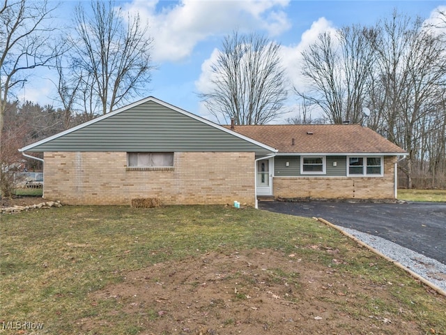 view of front of home with aphalt driveway, a front yard, and brick siding