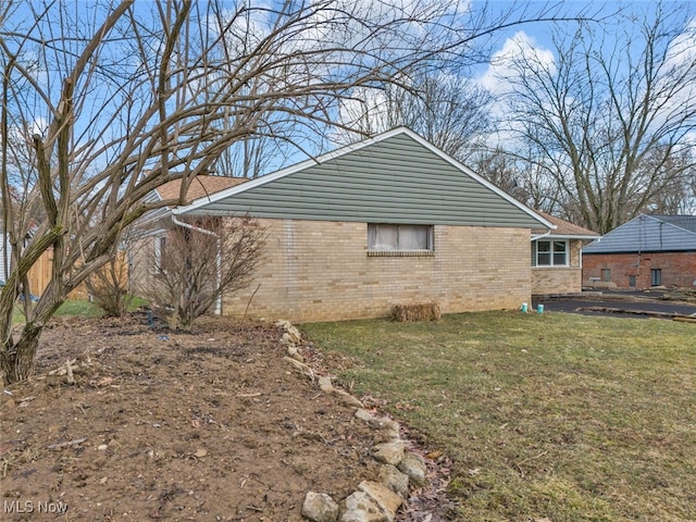 view of side of property featuring brick siding and a yard