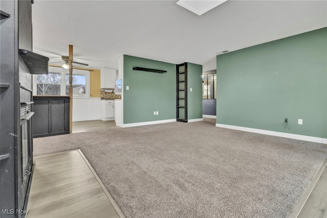 unfurnished living room with light carpet, baseboards, and a ceiling fan