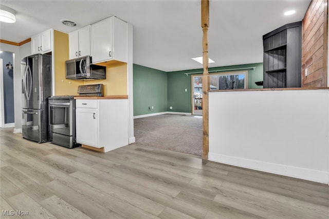 kitchen featuring stainless steel appliances, light wood-style flooring, open floor plan, white cabinets, and baseboards