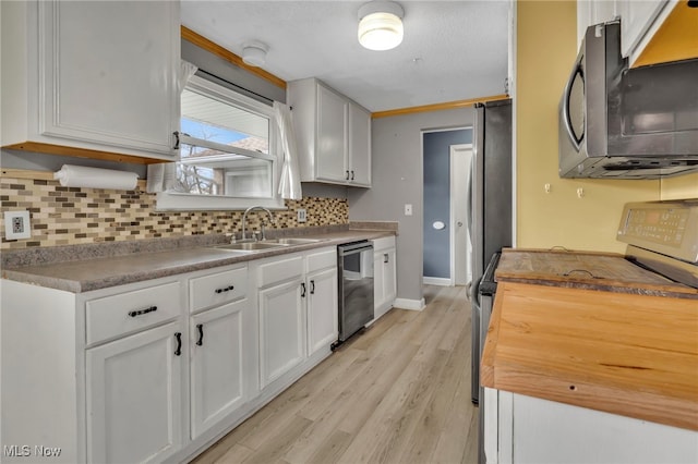 kitchen with decorative backsplash, stainless steel appliances, light wood-style floors, white cabinetry, and a sink