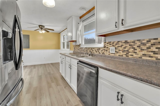 kitchen featuring stainless steel appliances, white cabinets, a wainscoted wall, and a sink