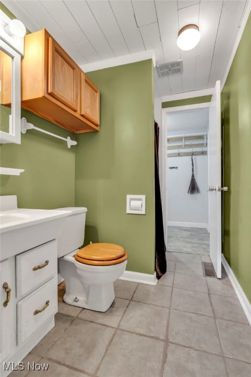 bathroom featuring toilet, vanity, baseboards, visible vents, and tile patterned floors