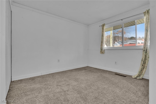 unfurnished room featuring carpet floors, visible vents, ornamental molding, and baseboards