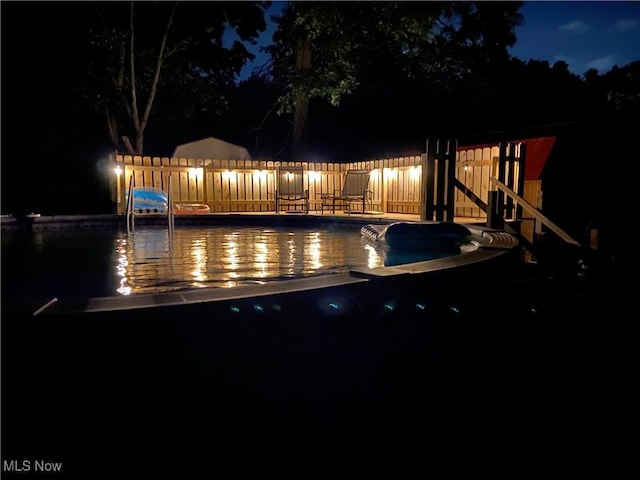 pool at twilight with fence and a swimming pool