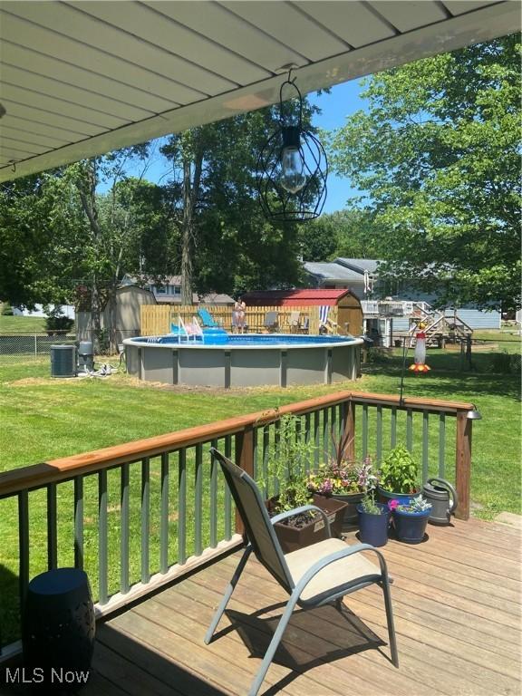 deck with a fenced in pool, a lawn, and fence