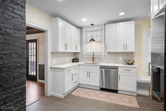 kitchen with white cabinets, decorative backsplash, appliances with stainless steel finishes, light countertops, and a sink