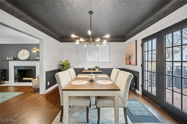 dining area with an inviting chandelier, a textured ceiling, a premium fireplace, and wood finished floors