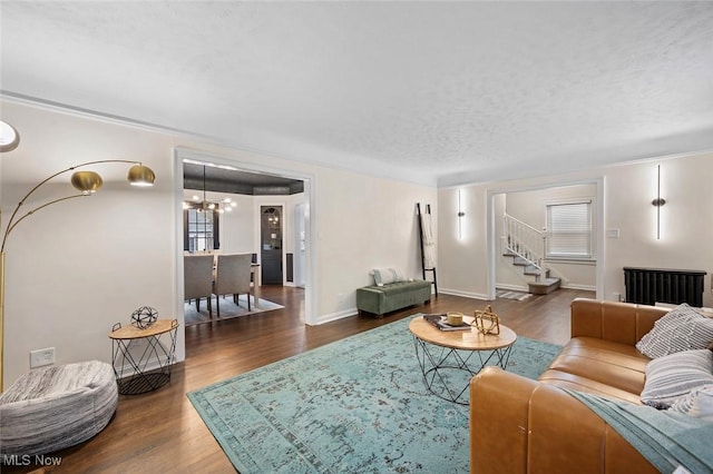 living room featuring a textured ceiling, a chandelier, wood finished floors, baseboards, and stairs