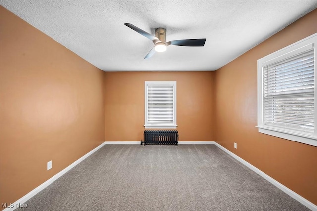 empty room featuring baseboards, ceiling fan, carpet flooring, and radiator