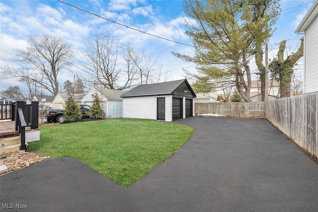 view of yard with an outdoor structure, fence, and a detached garage