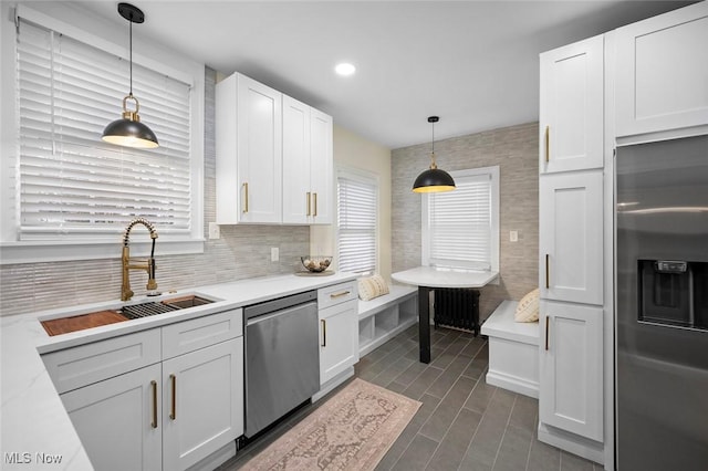 kitchen with pendant lighting, light countertops, appliances with stainless steel finishes, white cabinetry, and a sink