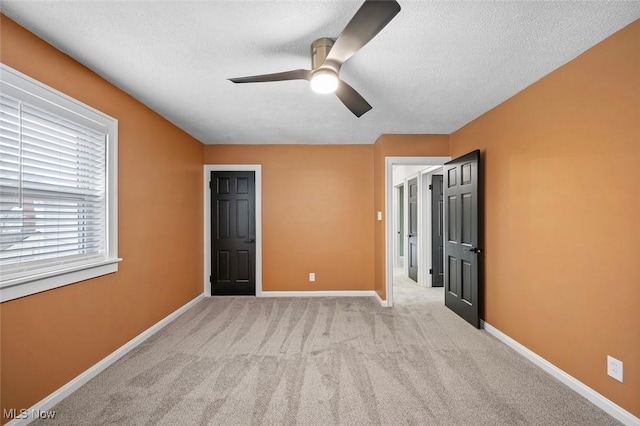 unfurnished room featuring a ceiling fan, light carpet, a textured ceiling, and baseboards