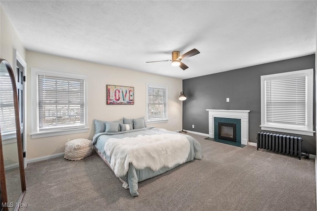 carpeted bedroom featuring a textured ceiling, radiator heating unit, a fireplace with flush hearth, and baseboards