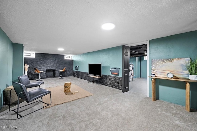 living room featuring a textured ceiling, carpet floors, a brick fireplace, and a textured wall