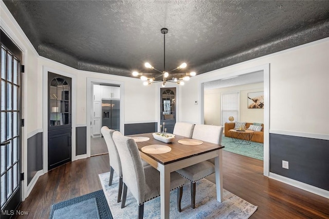 dining room with dark wood-type flooring, a textured ceiling, baseboards, and an inviting chandelier