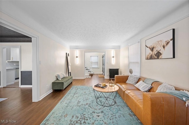 living area featuring baseboards, a textured ceiling, stairway, and wood finished floors