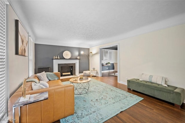 living room featuring a textured ceiling, a fireplace, wood finished floors, and baseboards