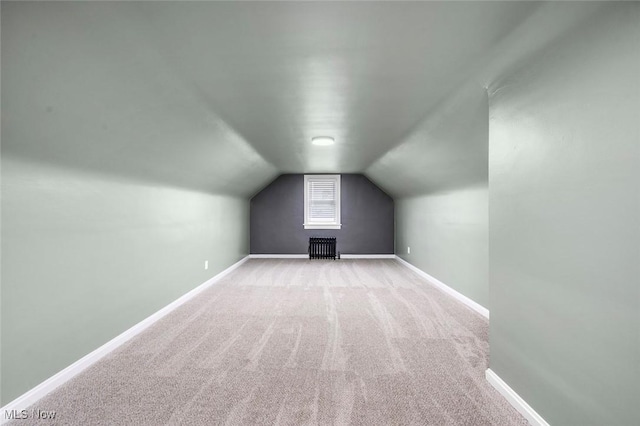 additional living space featuring lofted ceiling, light carpet, and baseboards