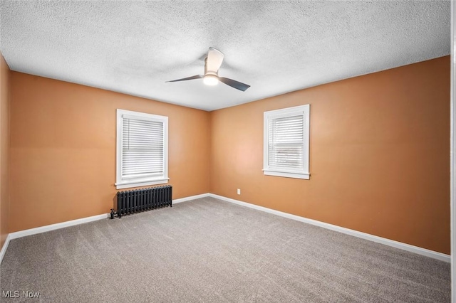 carpeted empty room featuring radiator, ceiling fan, a textured ceiling, and baseboards