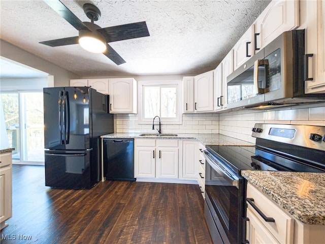 kitchen featuring black appliances, dark wood-type flooring, a sink, and light stone counters