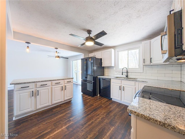 kitchen featuring dark wood-style floors, light stone counters, white cabinets, a sink, and black appliances