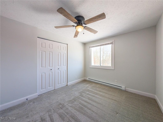 unfurnished bedroom with ceiling fan, a textured ceiling, a baseboard heating unit, baseboards, and a closet