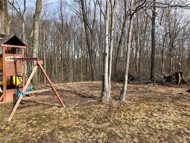 view of yard featuring a forest view and a playground