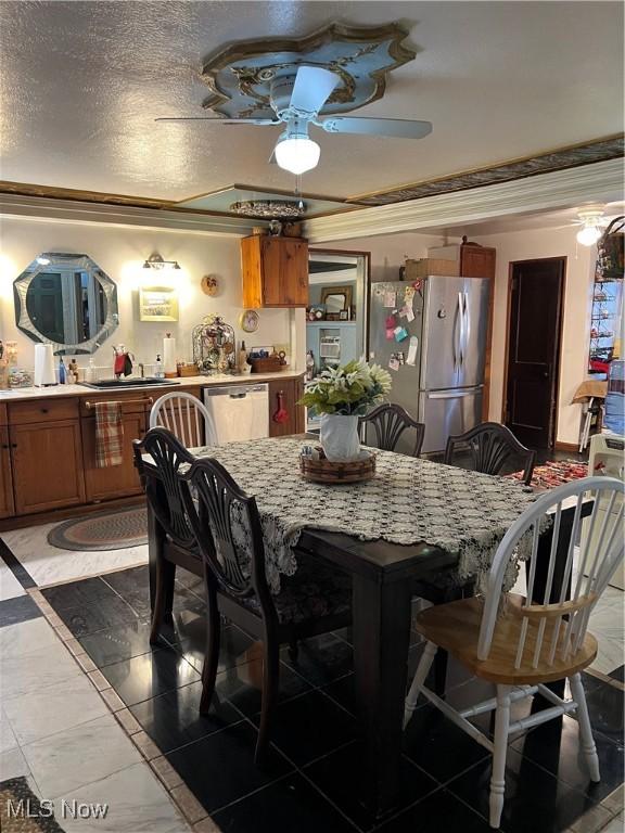 dining space featuring a textured ceiling, a ceiling fan, and crown molding