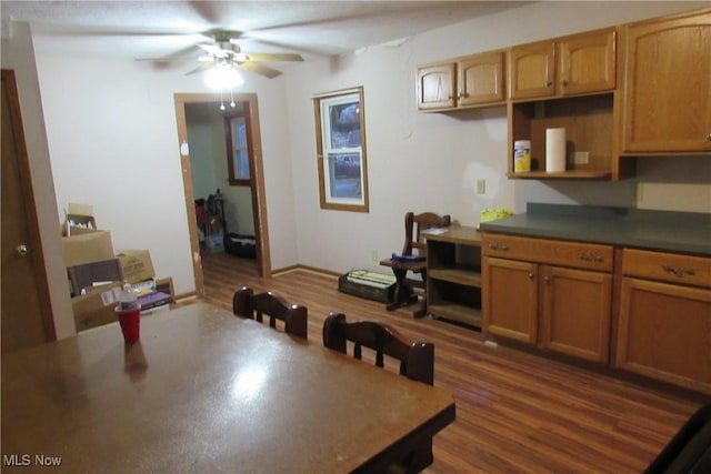 kitchen featuring a ceiling fan, dark countertops, brown cabinets, and dark wood finished floors