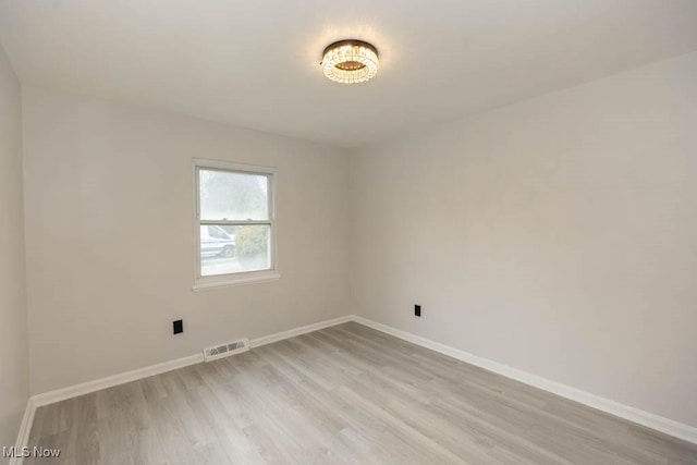 spare room with light wood-style flooring, visible vents, and baseboards