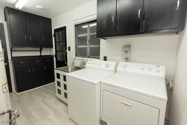 laundry room with washer and clothes dryer, a sink, cabinet space, and light wood-style floors