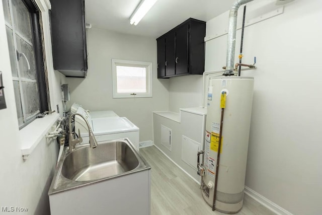 laundry area featuring washer and clothes dryer, light wood finished floors, water heater, cabinet space, and a sink