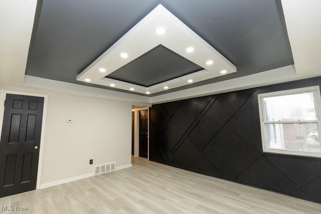 unfurnished room with recessed lighting, a raised ceiling, visible vents, and light wood finished floors