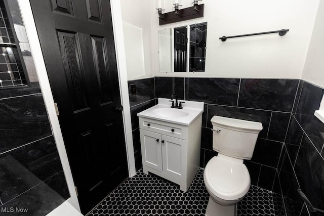 bathroom featuring tile patterned flooring, vanity, toilet, and tile walls