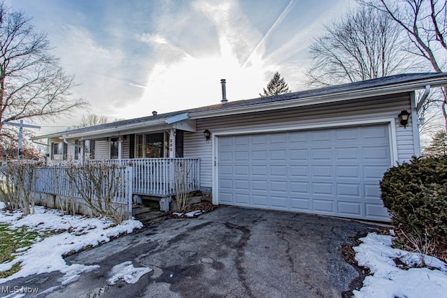 single story home featuring an attached garage, covered porch, and aphalt driveway