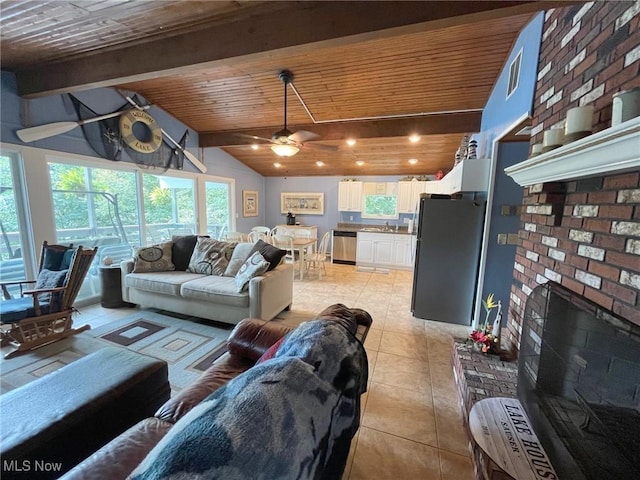 living area with a fireplace, light tile patterned floors, lofted ceiling with beams, ceiling fan, and wooden ceiling