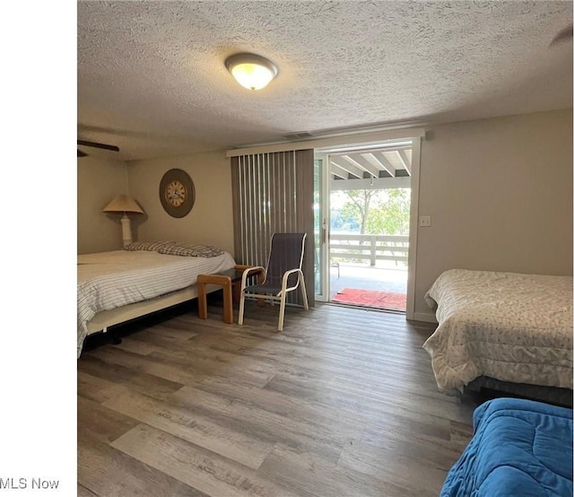 bedroom featuring a textured ceiling, access to outside, and wood finished floors