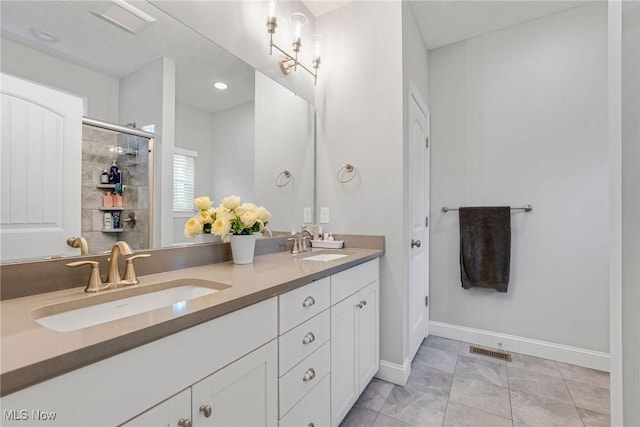 bathroom with double vanity, a sink, visible vents, and baseboards