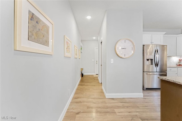 corridor with light wood-style flooring, baseboards, and recessed lighting