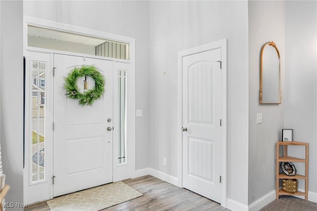 foyer with light wood-style flooring and baseboards