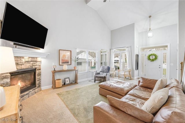 carpeted living room with baseboards, a fireplace, and high vaulted ceiling