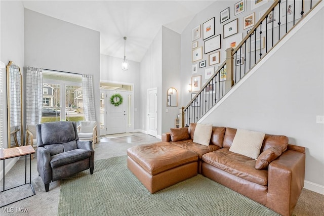 living room featuring carpet floors, baseboards, a high ceiling, and stairs