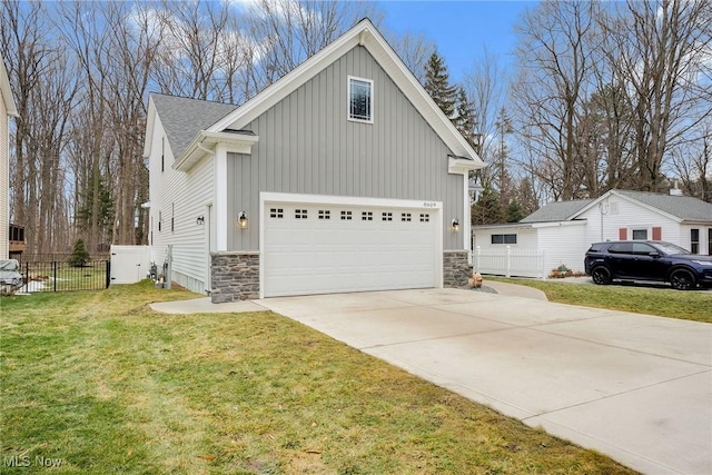 view of side of home with a garage, concrete driveway, stone siding, fence, and a yard