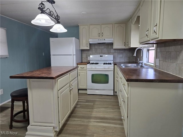 kitchen featuring under cabinet range hood, white appliances, wood finished floors, wood counters, and tasteful backsplash