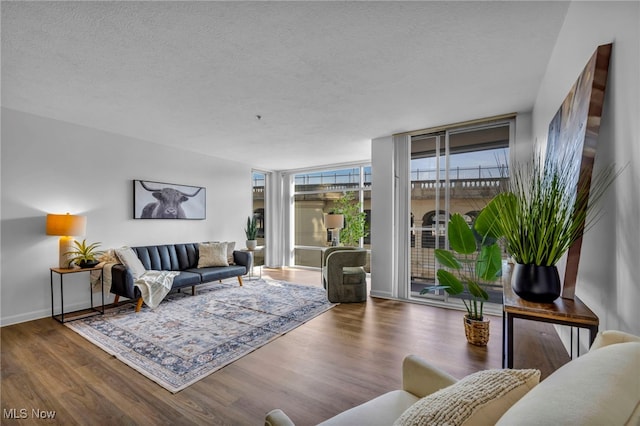 living area with a textured ceiling, floor to ceiling windows, wood finished floors, and baseboards